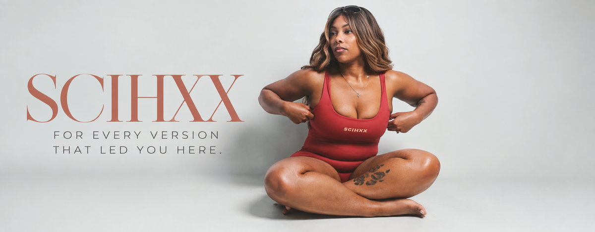 A woman sits cross-legged on a light gray studio background wearing a red one-piece swimsuit with the brand name SCIHXX printed on the chest. Large SCIHXX branding appears on the left side of the image with the tagline 'FOR EVERY VERSION THAT LED YOU HERE.